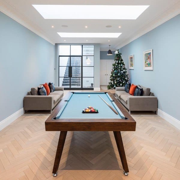Modern basement game room with pool table, cove ceiling lighting, skylights, and Christmas decor.