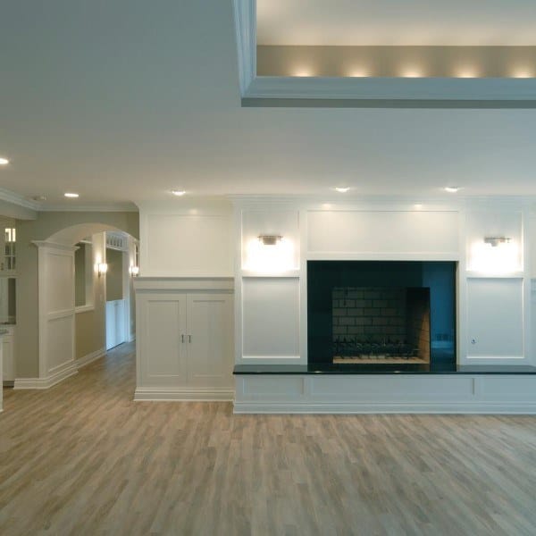 Spacious living room with recessed ceiling lights, fireplace, and light wood flooring.