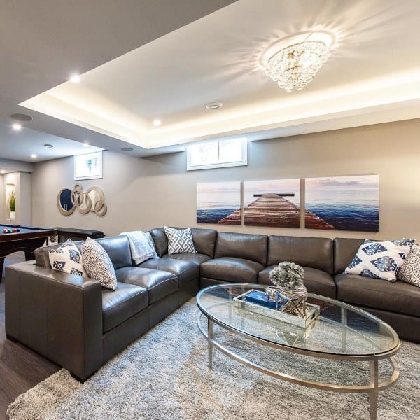 Cozy basement living area with sectional sofa, crystal chandelier, and modern wall art.