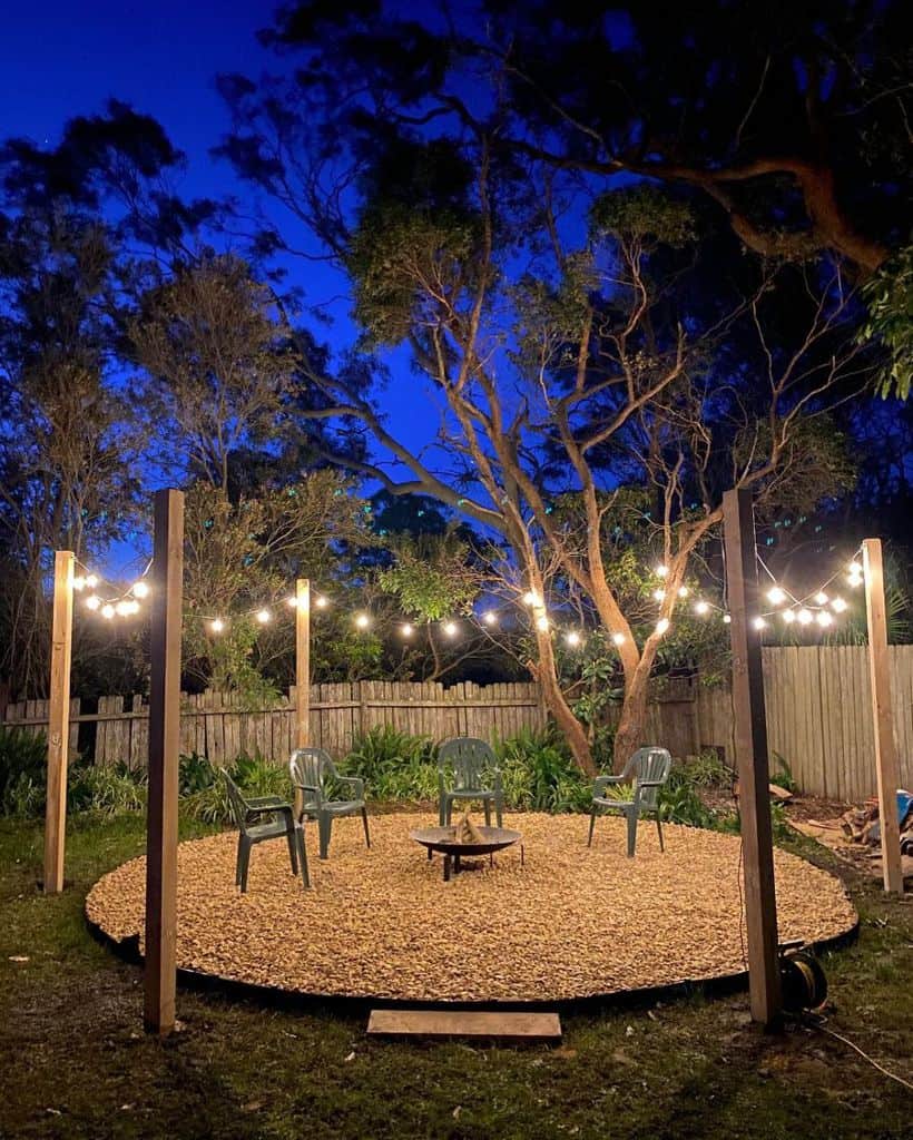 gravel outdoor area with fire pit green plastic chairs fairy lights