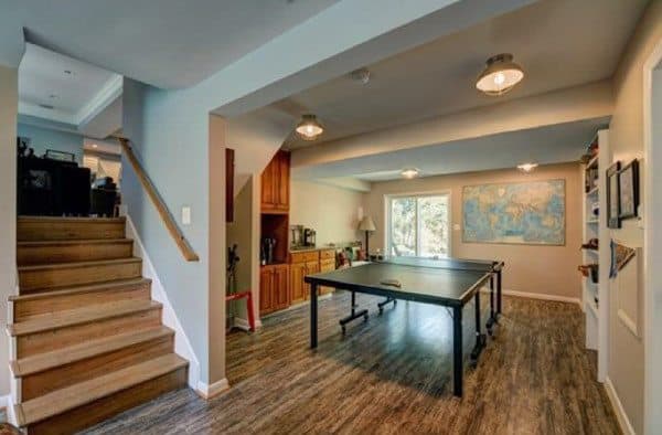 Basement game room with wood flooring, pendant lighting, and a table tennis setup.