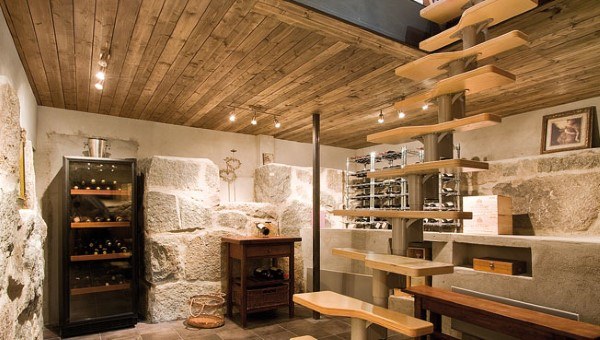 Basement wine cellar with wooden ceiling, stone walls, spiral staircase, and track lighting.