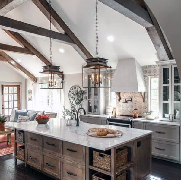 Rustic kitchen with exposed beams, marble island, pendant lighting, and farmhouse-style cabinets.