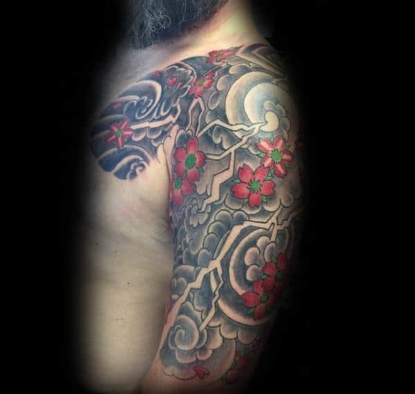 Traditional Japanese half-sleeve tattoo featuring bold lightning bolts, swirling clouds, vibrant red cherry blossoms, and a glowing full moon