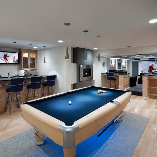 Modern basement with light wood pool table, sleek pendant lights, and bar seating area.
