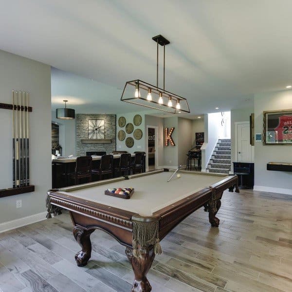 Basement with traditional wood pool table, rectangular pendant light, and bar area with seating.