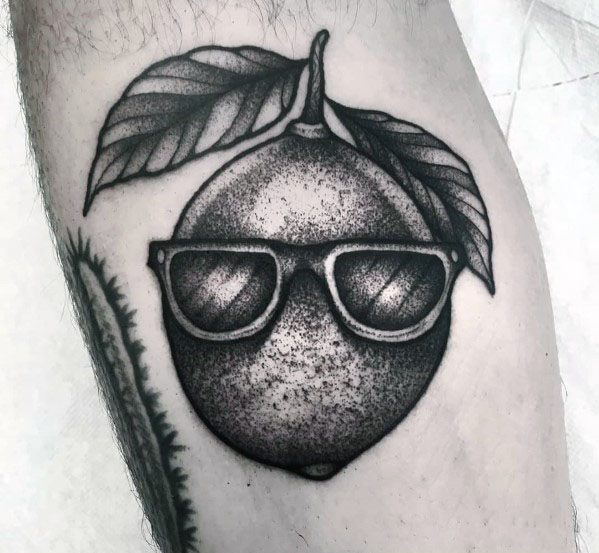 Cool black and grey lime tattoo with shading details, featuring sunglasses and leaves for a fun and stylish citrus-inspired design.