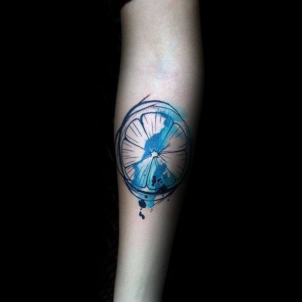 Artistic watercolor-style lime slice tattoo with bold blue splashes, creating a unique and modern citrus-inspired design.