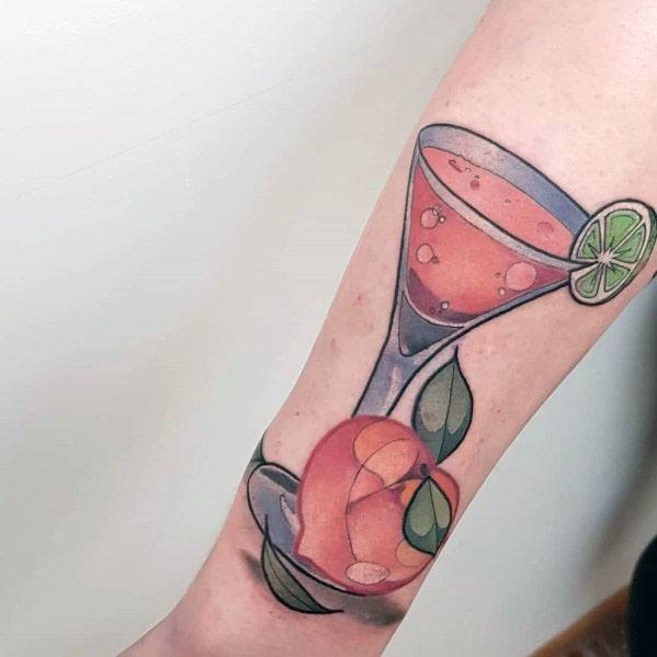 Elegant cocktail tattoo featuring a martini glass with a pink drink, a lime wedge garnish, and a peach, creating a stylish and refreshing design.