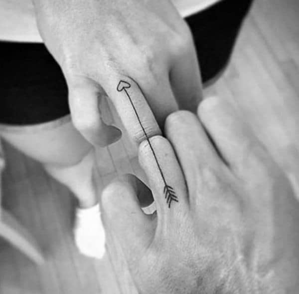Matching finger tattoos forming a complete arrow with a heart tip, symbolizing love, connection, and being each other's target.