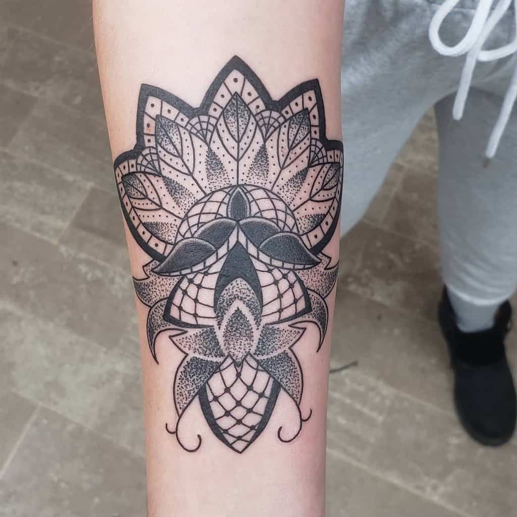 Intricate blackwork lace tattoo on forearm featuring a mandala-inspired floral design with dot shading and geometric patterns.