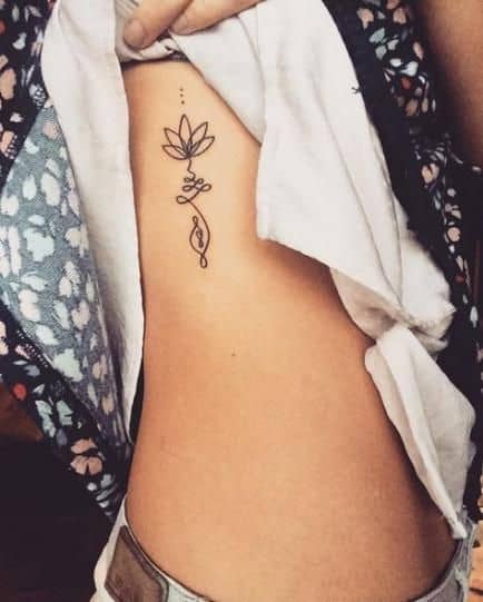 Unalome tattoo with a lotus on the ribcage, symbolizing spiritual growth, enlightenment, and the journey toward inner peace.