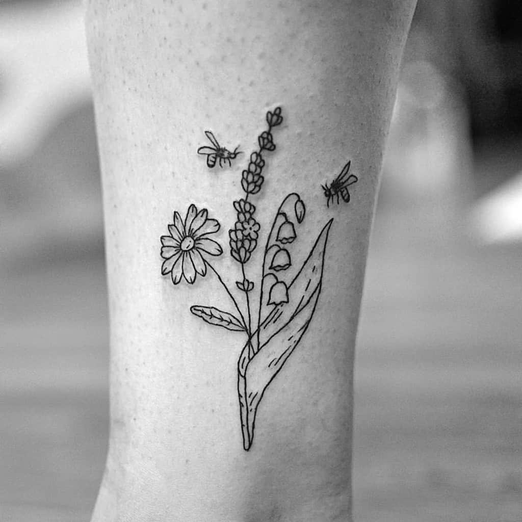Minimalist fine-line floral tattoo featuring Lily of the Valley, daisies, lavender, and bees, creating a delicate nature-inspired design