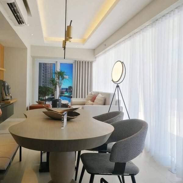 Modern dining room with flowing white linen curtains, a sculptural table, and stylish chairs.