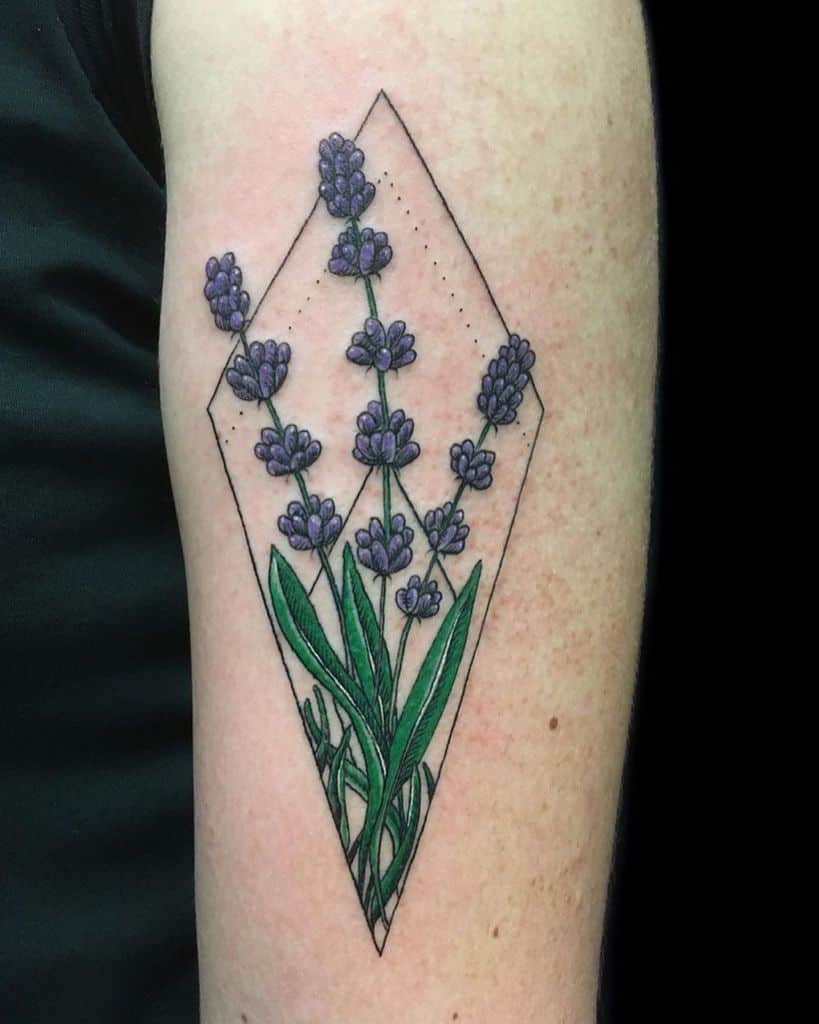 A geometric tattoo of lavender flowers and leaves inside a diamond shape, with delicate purple blooms and green stems, placed on the forearm.