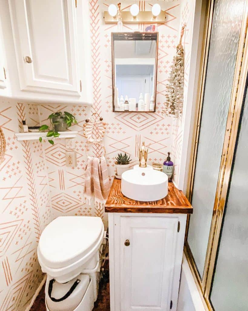 Small bathroom with abstract patterned wallpaper, vessel sink, and wooden countertop.
