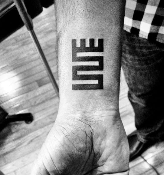 Wrist tattoo with the word "LOVE" written vertically in a unique block font