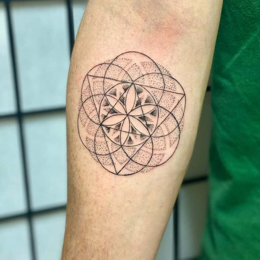 Forearm tattoo featuring a delicate geometric mandala with fine dot work, creating a symmetrical and minimalist sacred design.