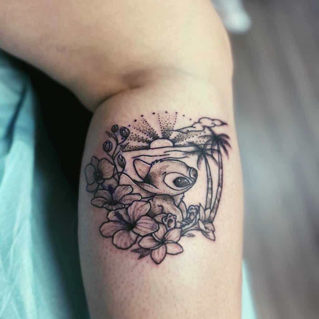 Black and gray tattoo of Stitch from Lilo & Stitch surrounded by tropical flowers, with a sun, clouds, and palm trees in the background, on the upper arm.