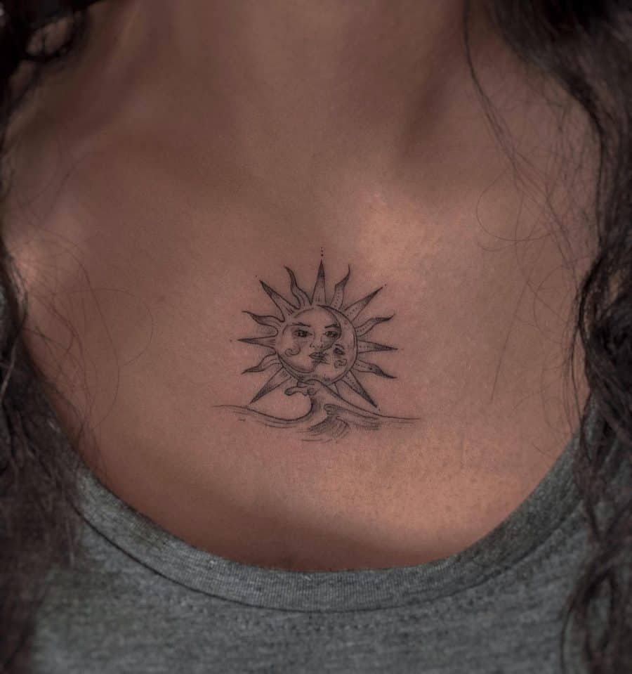 Small black ink tattoo of a sun and moon with faces, positioned above ocean waves, featuring fine linework and subtle shading on the chest.