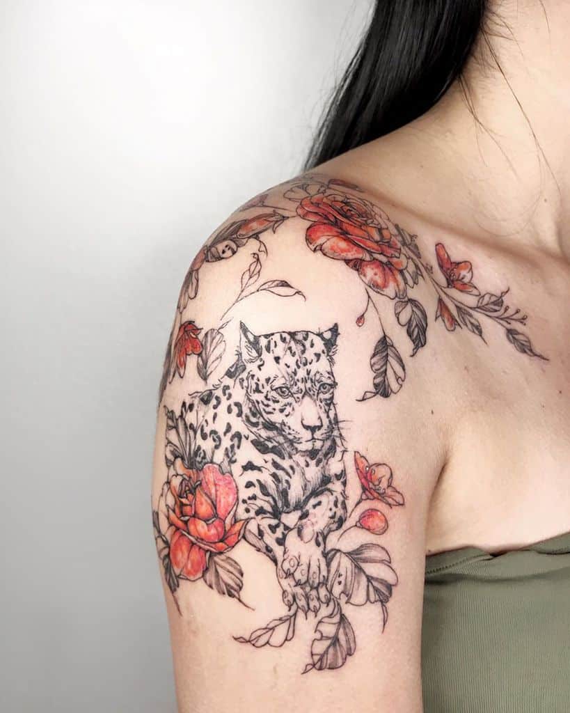 A beautiful tattoo of a jaguar surrounded by colorful roses, blending intricate details and soft shading with vibrant hues, placed on the shoulder and upper arm.