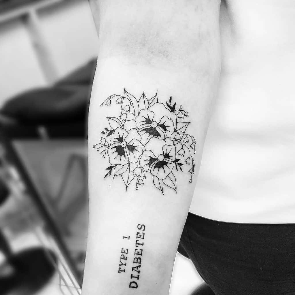 Black ink floral tattoo featuring bold pansies and delicate Lily of the Valley flowers, paired with a 'Type 1 Diabetes' script