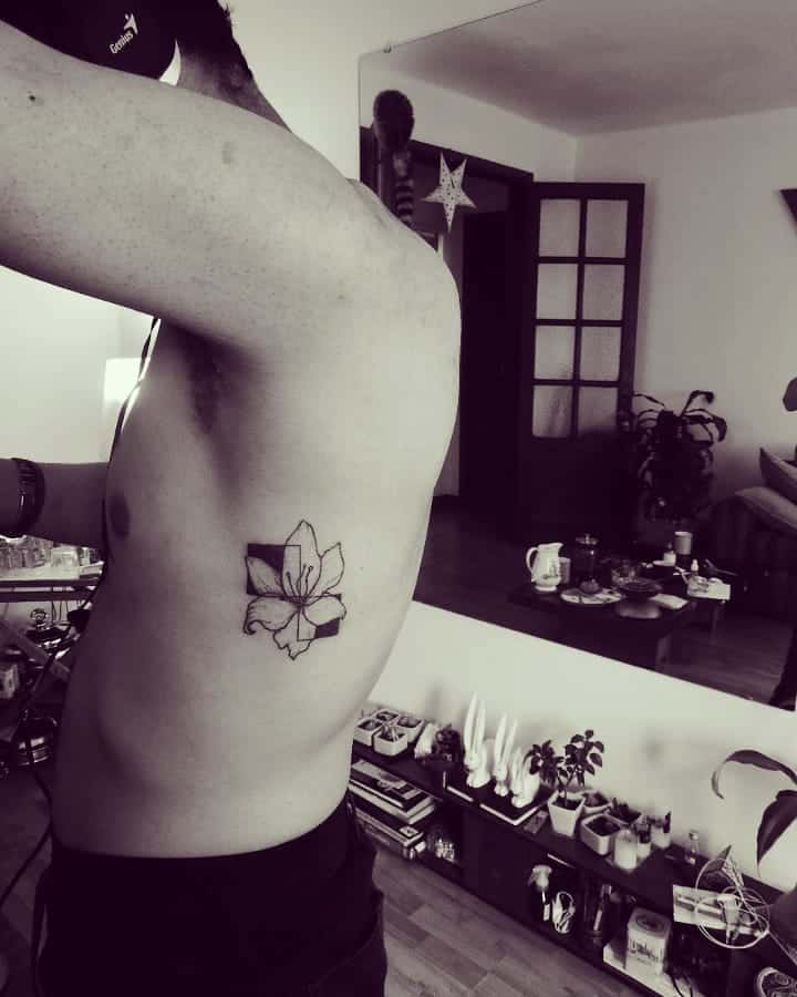 Minimalist black and grey tattoo of a lily with geometric shading, blending floral elegance with modern design