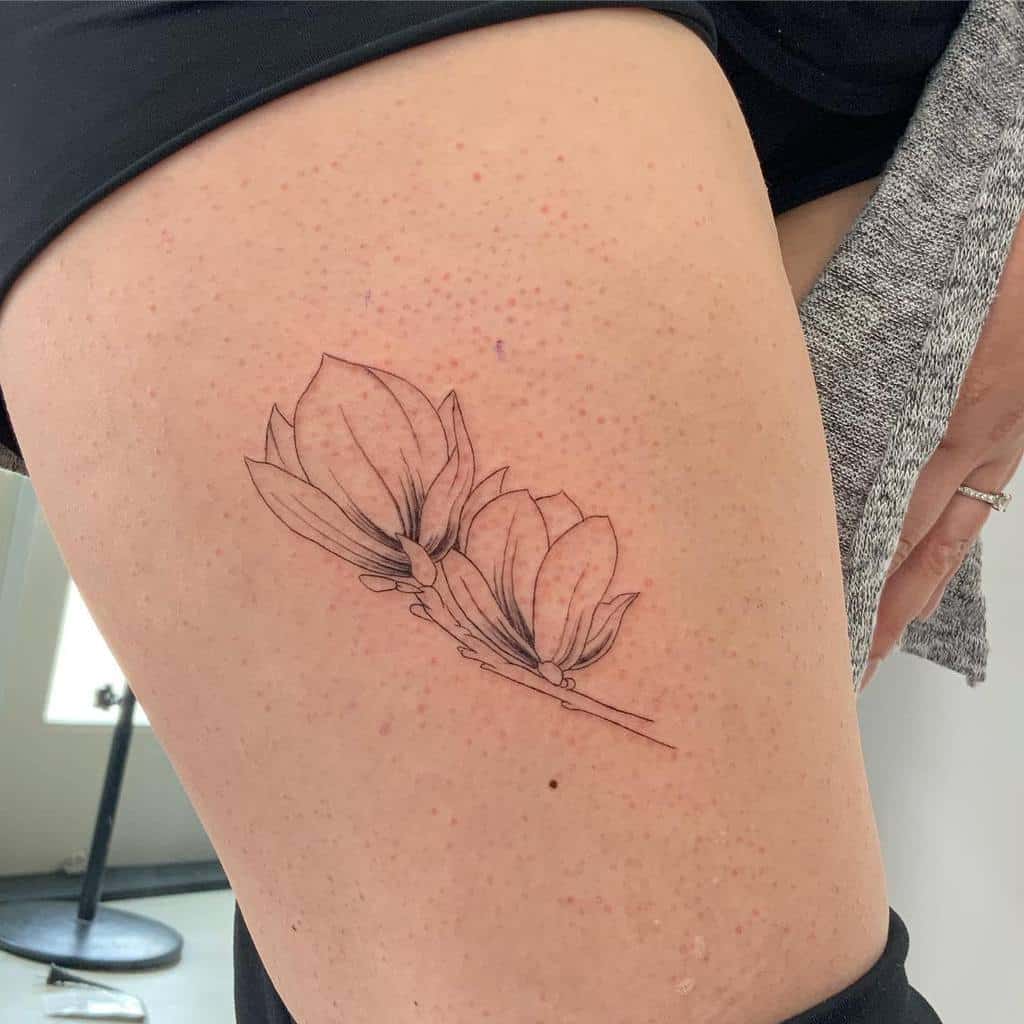 Line art tattoo of two magnolia flowers gracefully adorning a thigh