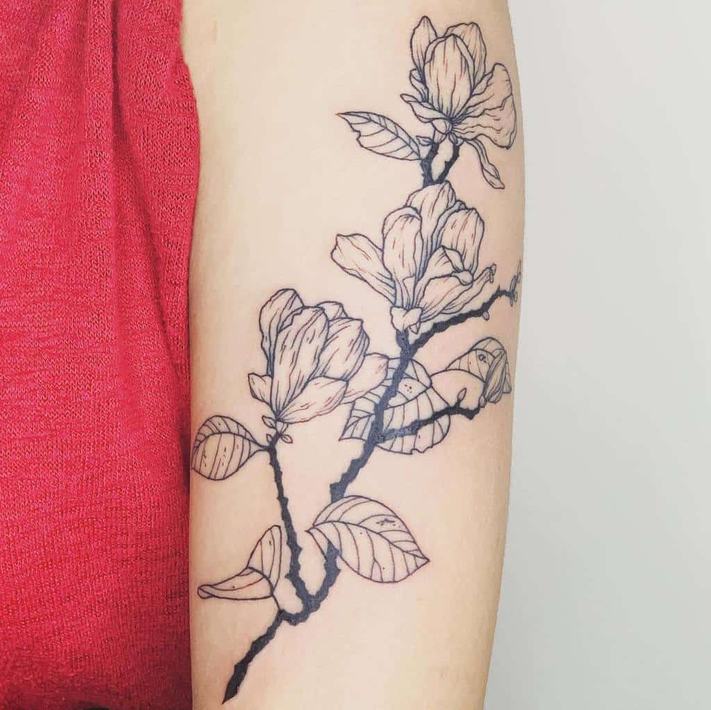 An exquisite line art tattoo of a magnolia branch, adorned with delicate flowers, graces the arm beautifully