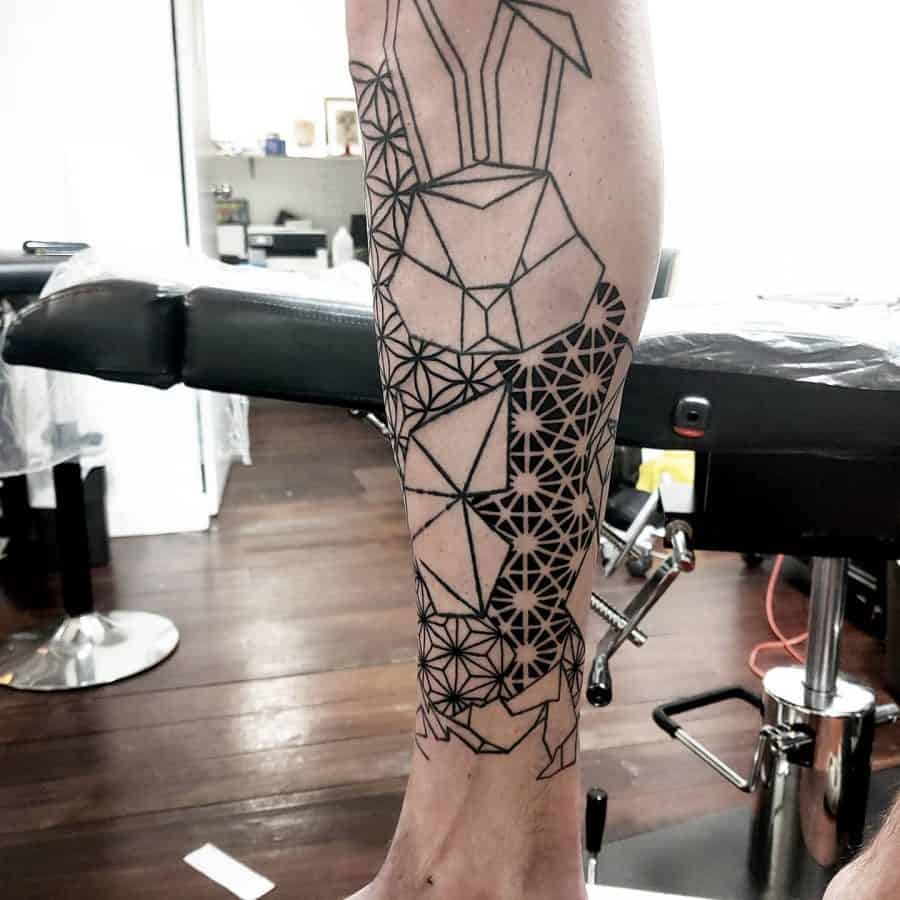 Leg tattoo featuring a geometric deer design with intricate line work and honeycomb patterns, creating a bold, modern abstract look.