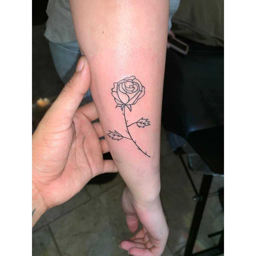 Line art rose tattoo on a forearm