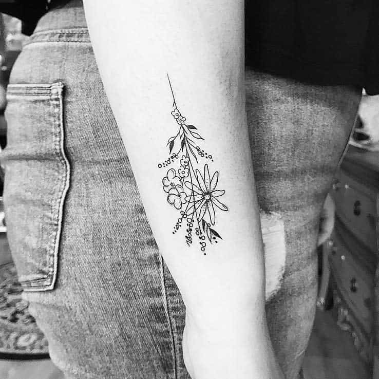 Simple linework tattoo of wildflowers and small leaves on the arm, featuring clean, minimalist black ink design