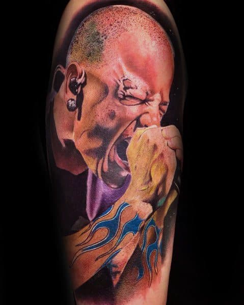 Realistic color tattoo of Chester Bennington mid-performance, capturing his raw emotion with detailed shading and iconic flame wrist tattoo.