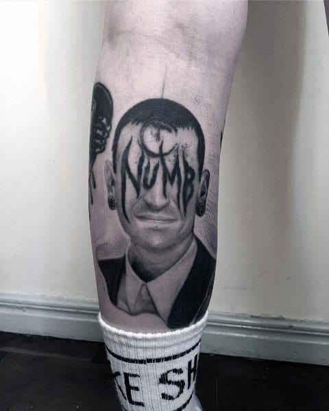 Black and gray tattoo of Chester Bennington with 'Numb' written across his face in a dripping font, symbolizing deep emotion and legacy.