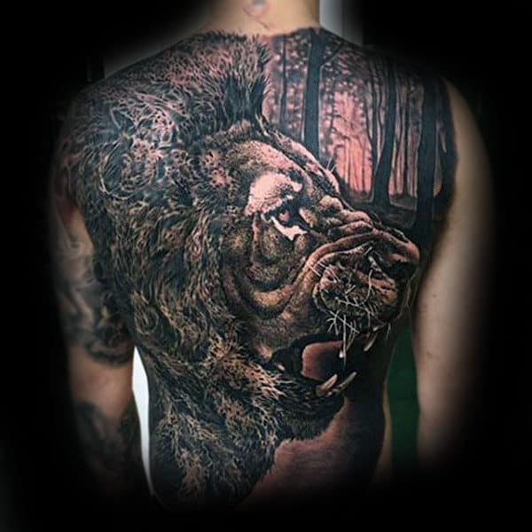 Person with a large, detailed lion tattoo on their back, blending into a forest scene