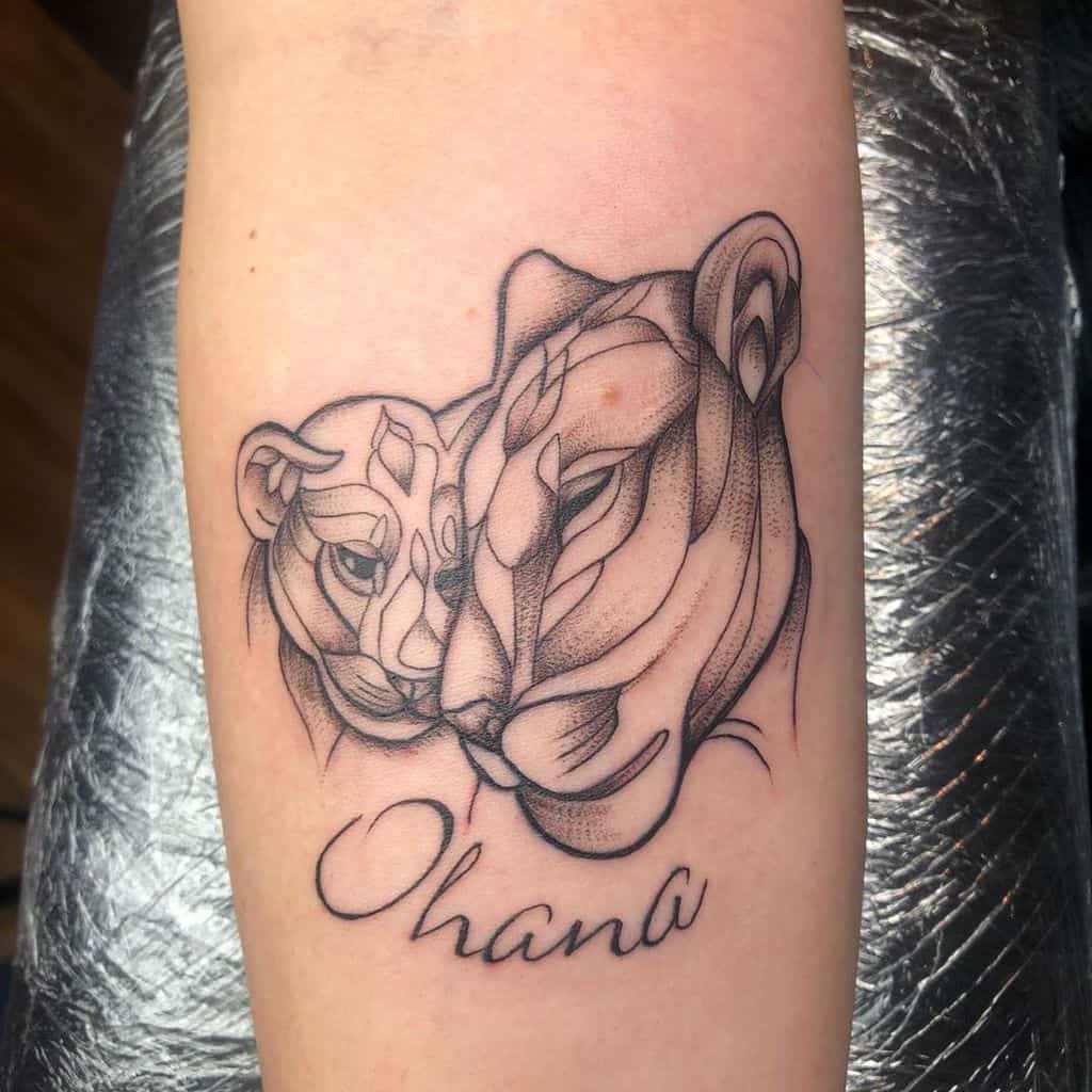 Fine-line tattoo of two lions with 'Ohana' written below, symbolizing family, strength, and deep bonds.