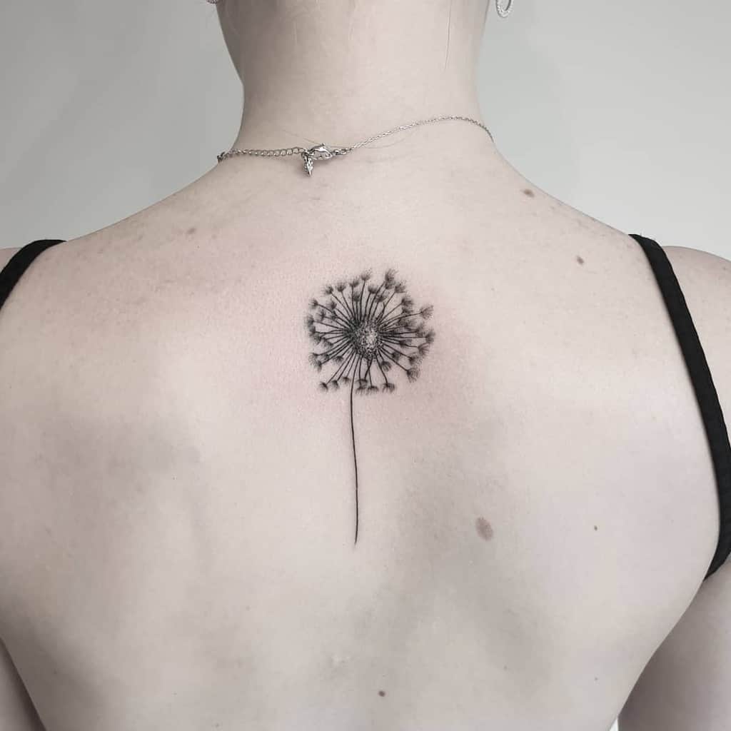Elegant dandelion tattoo centered on the upper back, featuring fine-line details, symbolizing wishes, growth, and new beginnings.