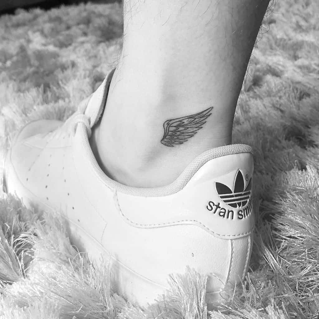 Small angel wing tattoo, creating a stylish and subtle design in black and white