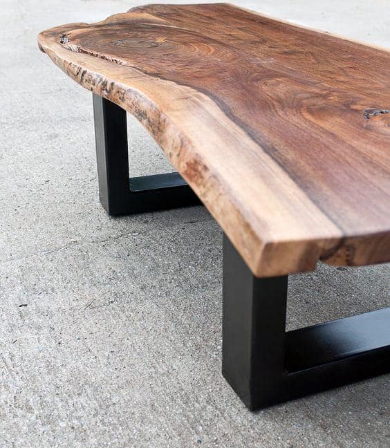 Wooden table with a live edge top and black metal legs on a concrete surface
