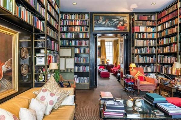 Cozy library room with a towering bookshelf, colorful cushions, and paintings on walls