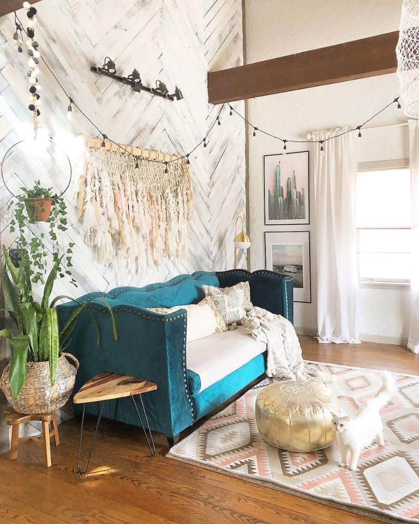 eal sofa in a bohemian living room with macrame wall art and a white cat on a patterned rug.