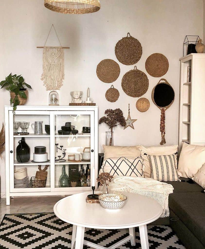 Bohemian living room with a white cabinet, wicker wall decor, patterned rug, and cozy cushions.