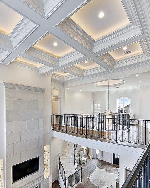 Spacious living room with coffered vaulted ceiling, crown molding lighting, and a stylish staircase