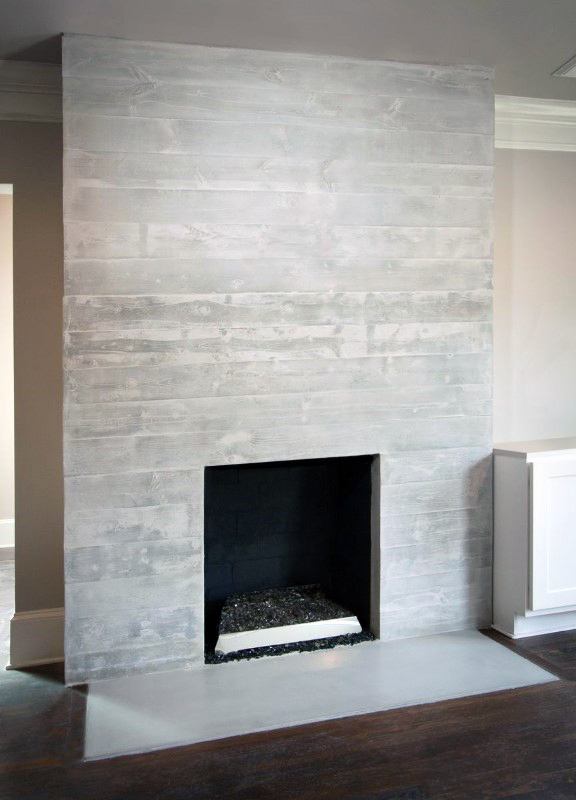 Simple board-formed concrete fireplace with a minimalist design and dark interior finish.