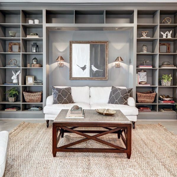 Cozy living room with gray built-in bookcases, a white sofa, woven rug, and a wooden coffee table