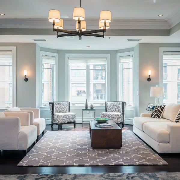 A spacious living room featuring elegant crown molding, modern furniture, and ample natural light from large windows, creating a cozy and sophisticated atmosphere