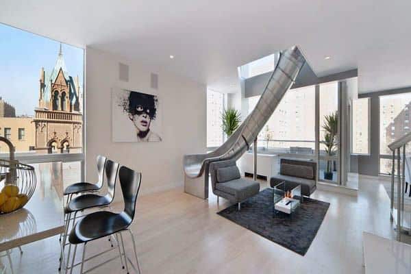 Modern apartment with a slide to the lower level, sleek furniture, and large windows offering city views