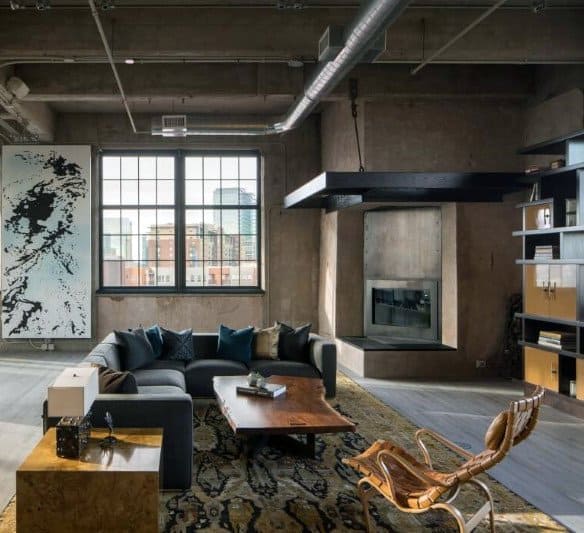 Industrial living room with a modern fireplace, exposed ductwork, and large city-view windows.