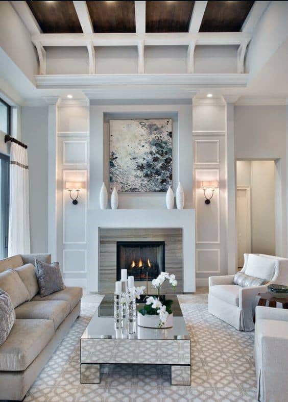 Elegant white fireplace with built-in paneling, decorative vases, modern artwork, and wall sconces.