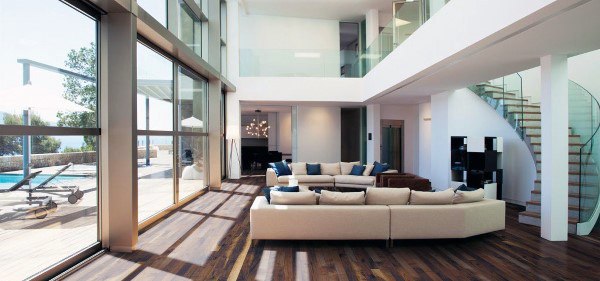 Spacious modern living room with large windows, wooden floors, and a view of the poolside patio from the staircase